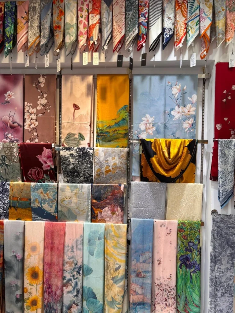 Assorted Chinese silk textiles and scarves featuring floral and landscape inspired patterns